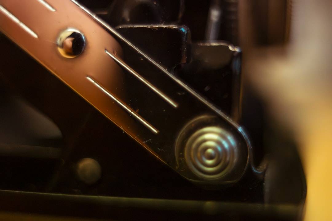 Close up of a metallic spring mechanism on black machinery.