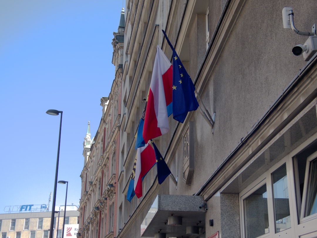 Polish and european union flags flying on a building.