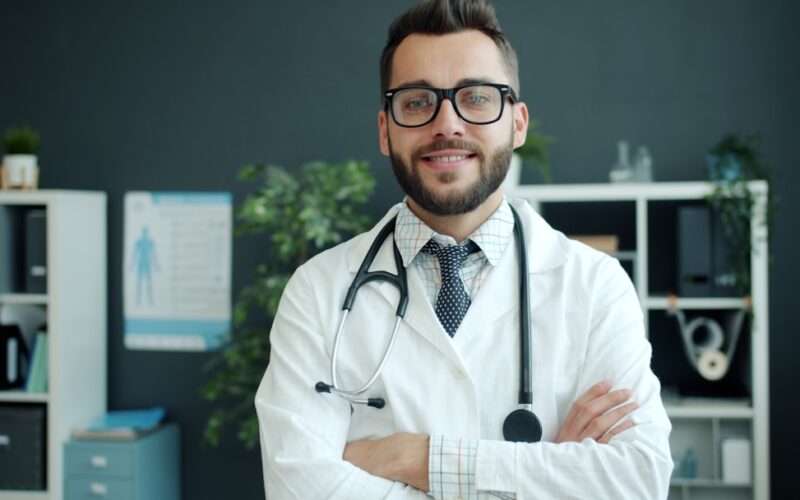 Chatgpt health — a smiling doctor with glasses and stethoscope stands arms crossed.