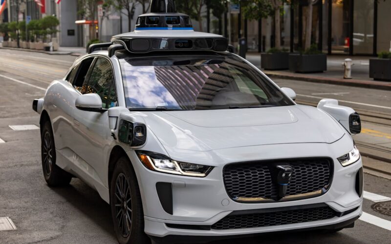 Robotaxi safety certification — a white self-driving car on a city street.