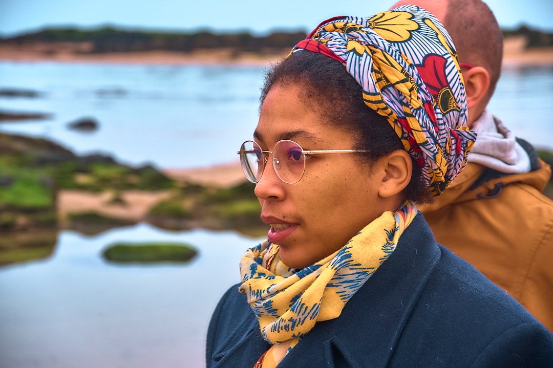 Woman with glasses and headscarf by the sea