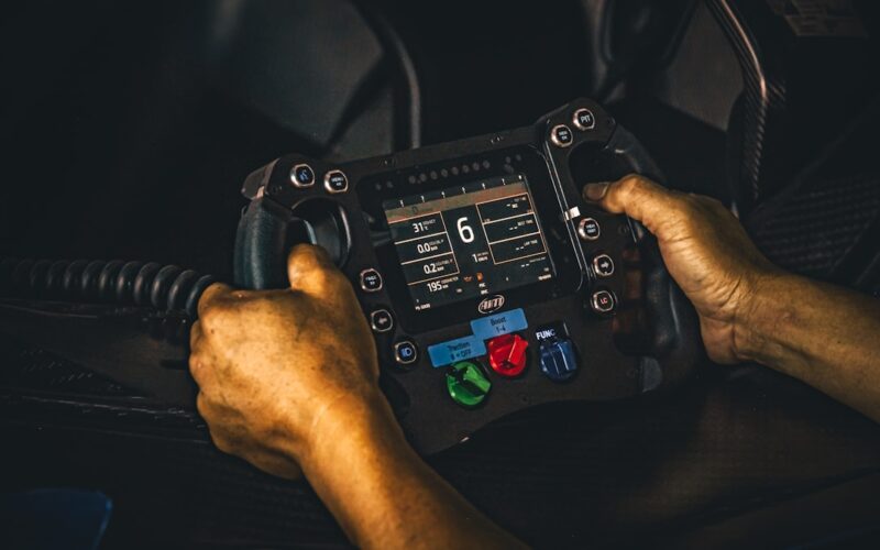 Tesla autopilot data — oily hands hold a professional racing steering wheel.