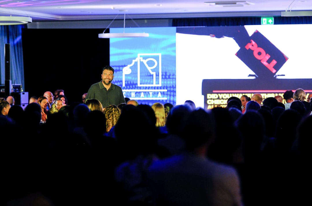 Man speaking on stage with audience watching